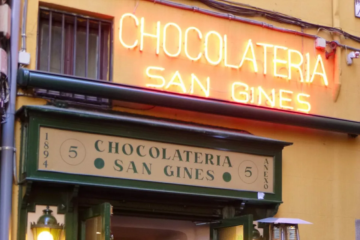 The illuminated storefront of Chocolatería San Ginés, with visitors queueing outside
