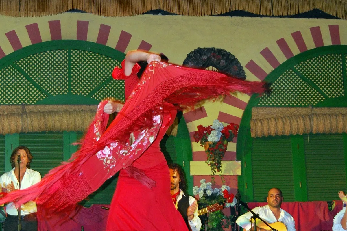 A flamenco dancer mid-performance in a red dress, with live guitar accompaniment