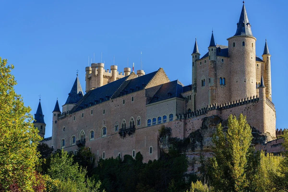 The fairytale towers of the Alcázar of Segovia against a clear blue sky